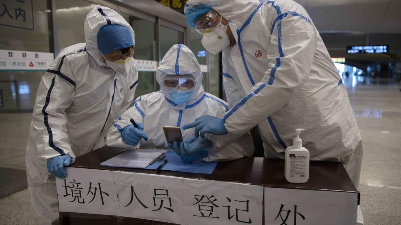 Health workers check details of a passenger arriving from beijing at the train station in Wuhan.