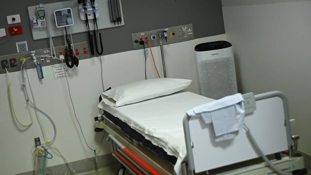 An empty hospital bed, with medical equipment next to it
