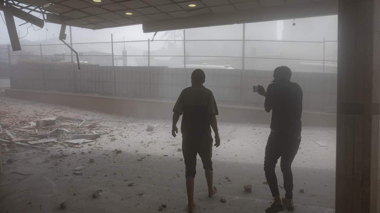 Two people walking through debris in Nasser Hospital.