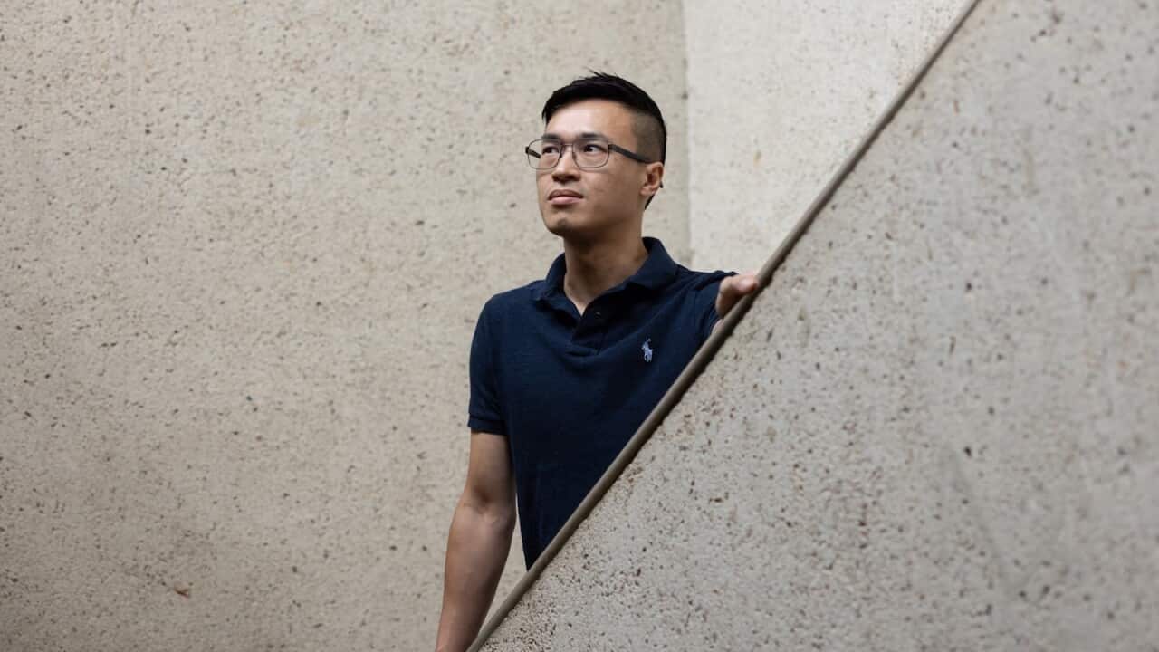 A man wearing a polo shirt standing behind a wall.