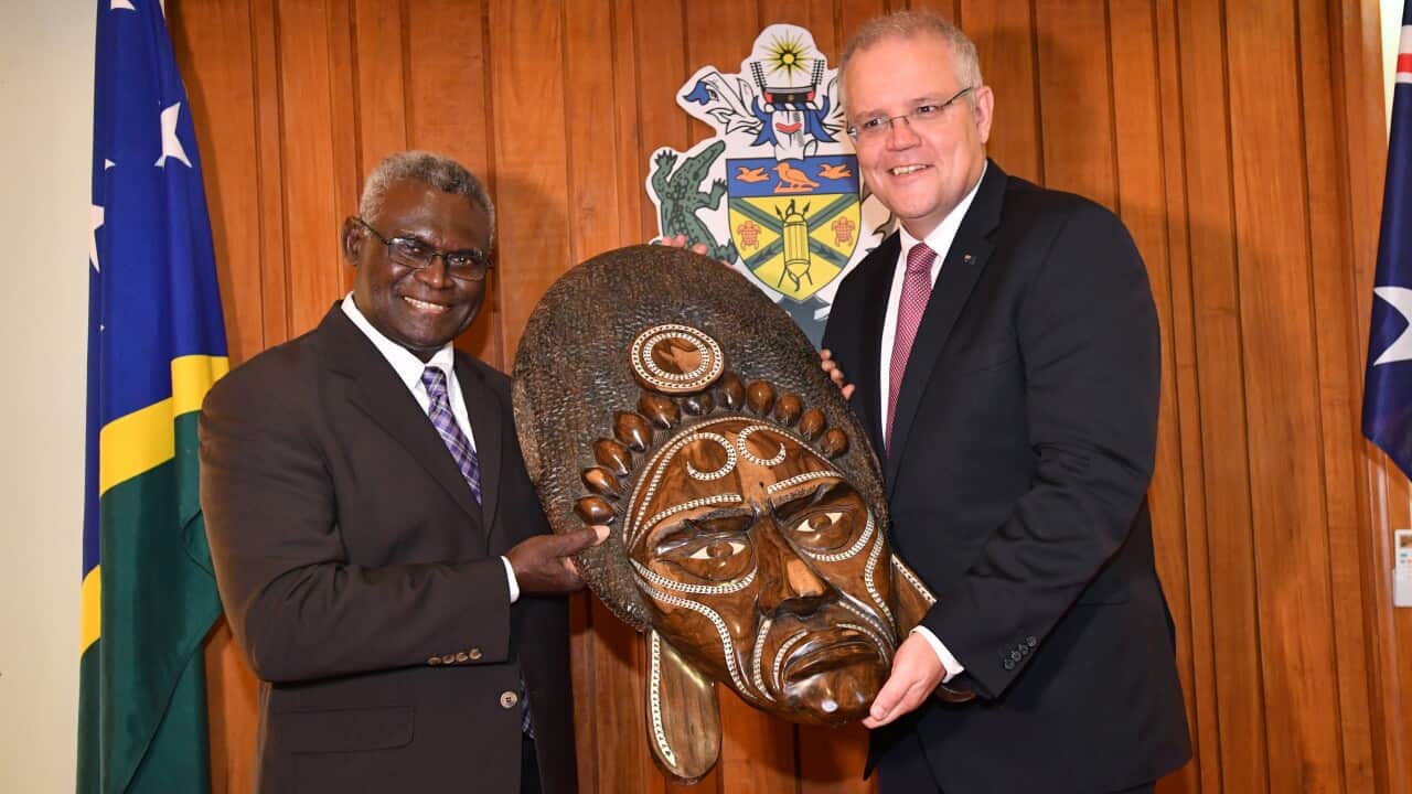 Solomon Islands Prime Minister Manasseh Sogavare (left) presents a traditional wood carving to the Australian Prime Minister Scott Morrison.