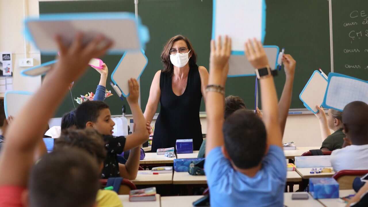 A teacher wearing a protective mask teaches in her classroom on the first day of the new school year in Nice, France.