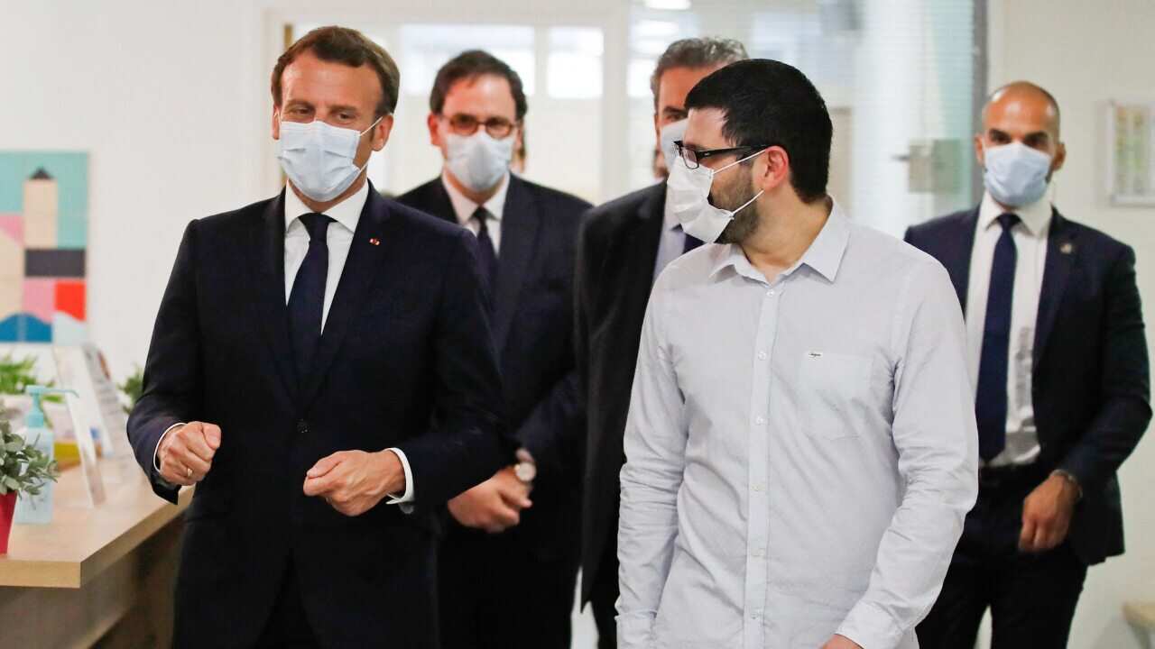 French President Emmanuel Macron, wearing a protective face mask, talks with health workers, 7 April, 2020.