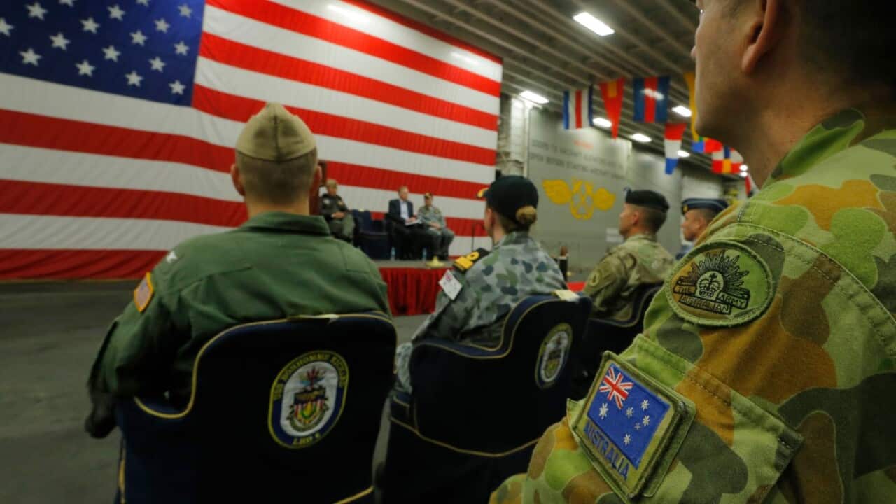 A member of the Australian Army sits in the audience alongside a U.S. flag as the backdrop of a ceremony marking the start of Talisman Saber 2017