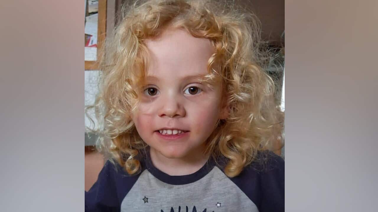 A small boy with long curly blonde hair