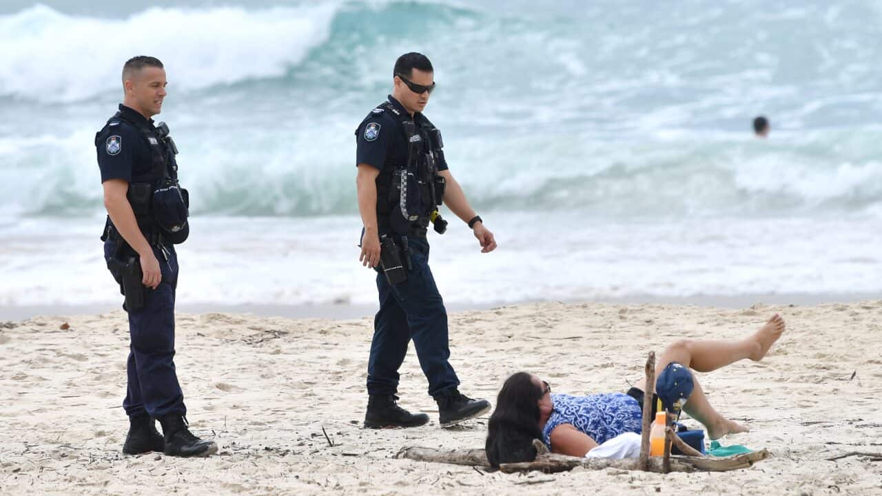 Queensland Police are seen moving on a sunbather from the beach at Burleigh Heads on the Gold Coast.