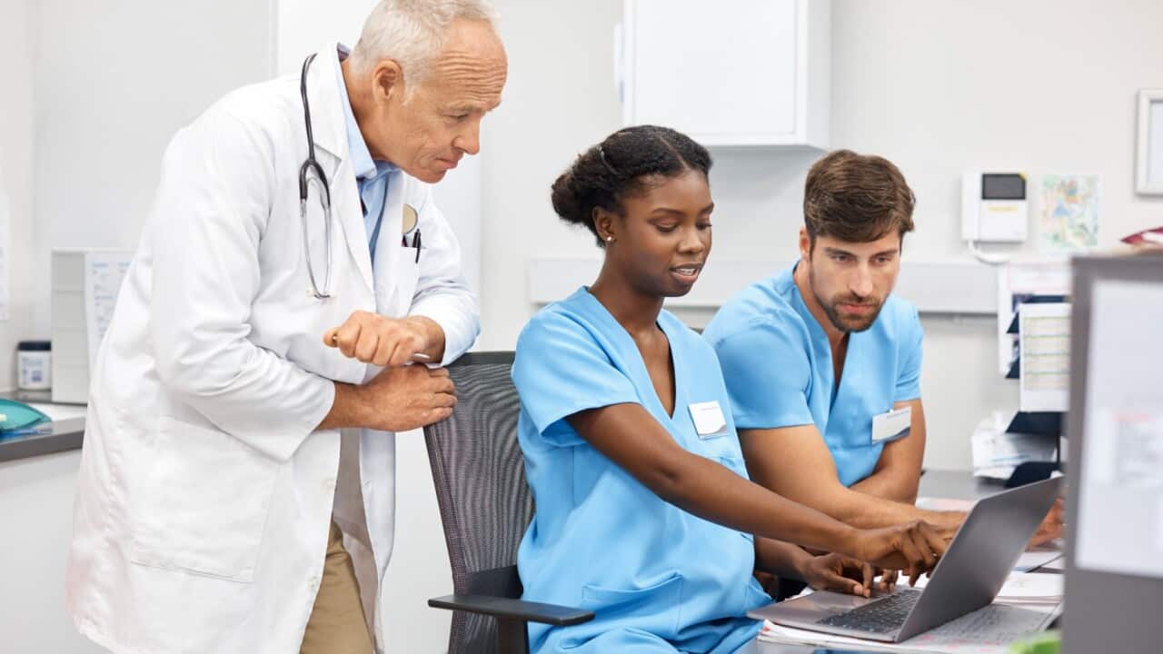 Medical professionals discussing over laptop. Confident nurses and doctor are working at hospital. They are wearing uniforms.