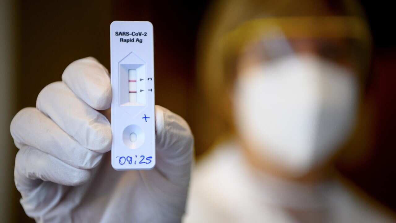 A health worker shows a positive SARS-CoV-2 Rapid Antigen Test from the Swiss multinational healthcare company Roche just after collecting a nose swab sample.