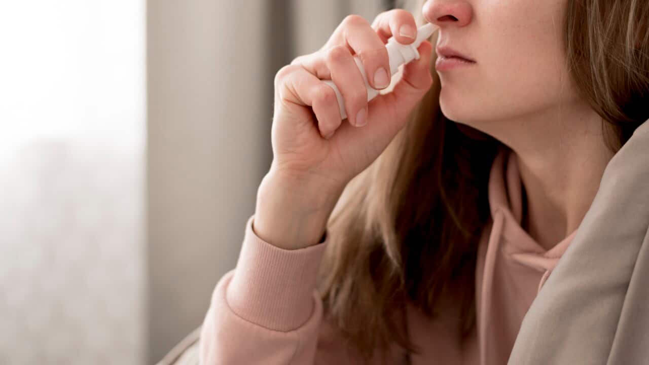 woman taking nasal spray treatment