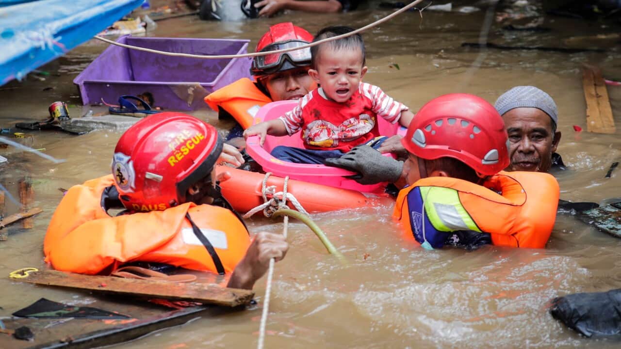 Indonesian rescuers evacuate a boy from a flooded area in Jakarta, Indonesia