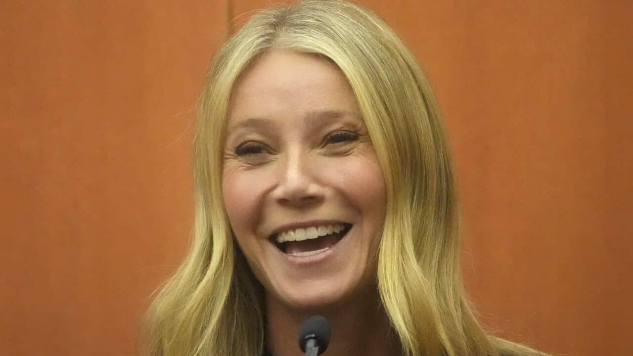 A woman speaking while seated in front of a microphone.