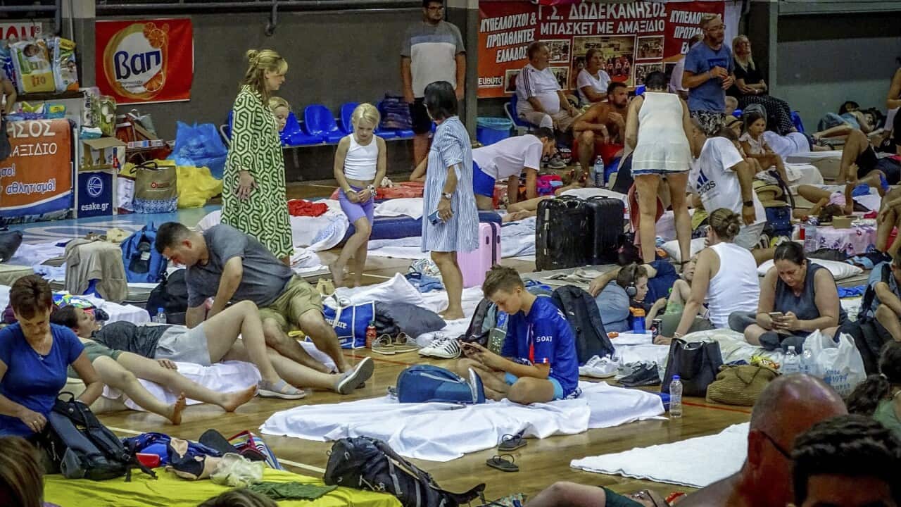 Evacuees sit inside a stadium following their evacuation on the island of Rhodes