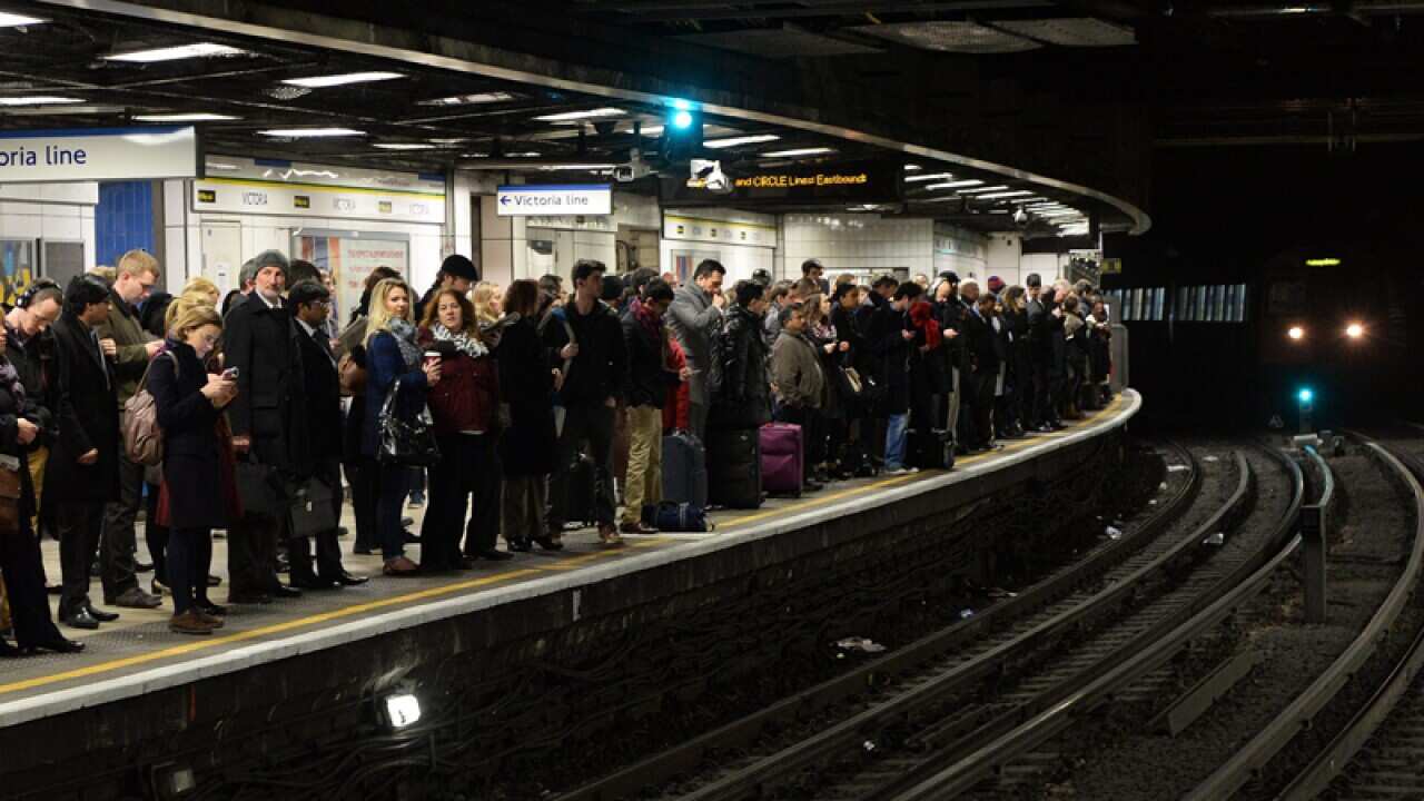 Commuters wait to board a limited service Tube train