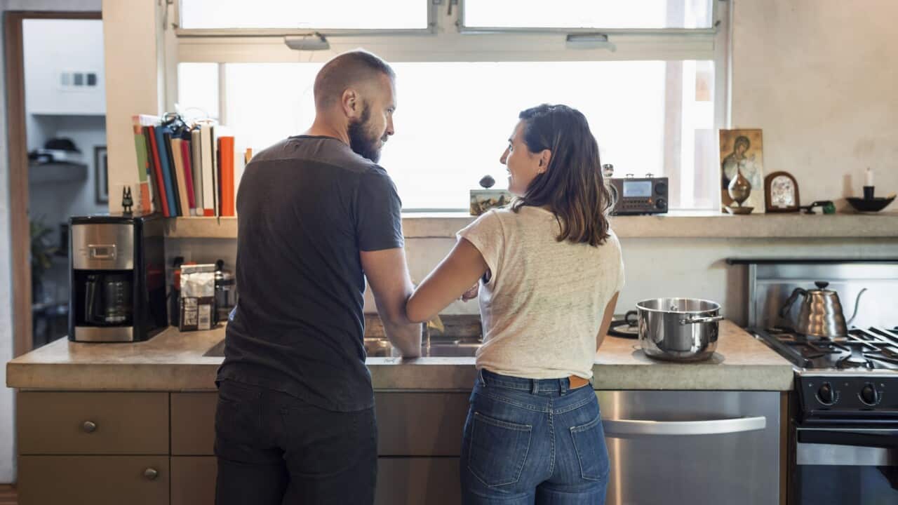 Rear view of couple looking at each other in kitchen