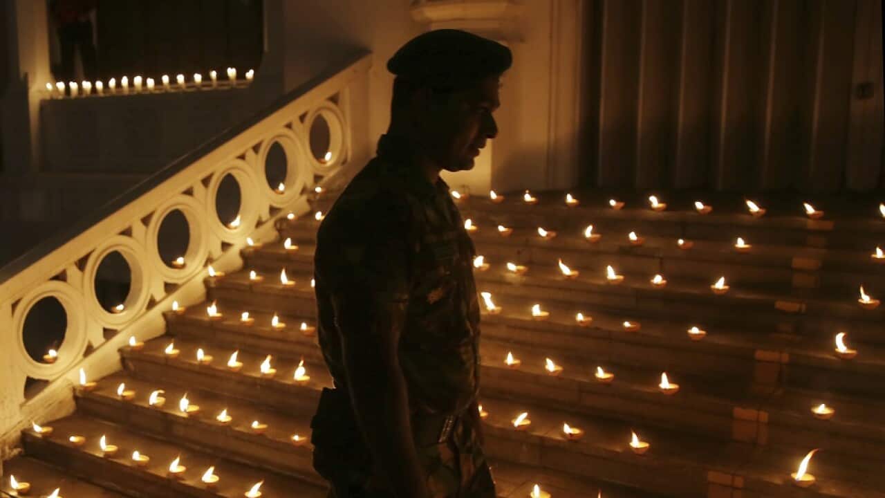 A Sri Lankan Army officer walks past lighted candles.