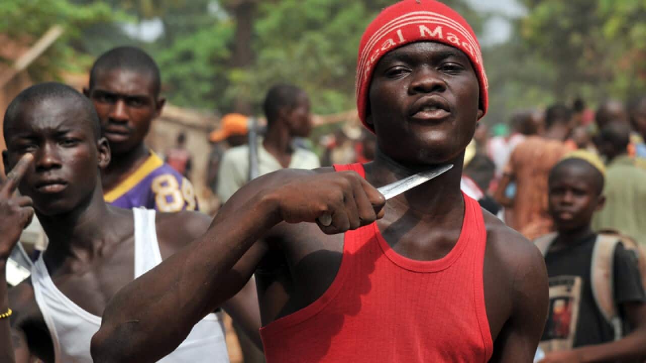 A man holds a knife to his throat