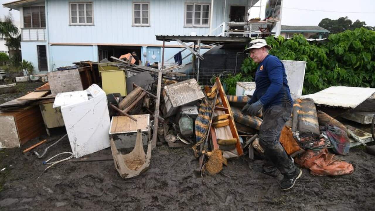 Chris Mitchell piles up flood damaged items out of his father in-law's house in the suburb of Rosslea in Townsville