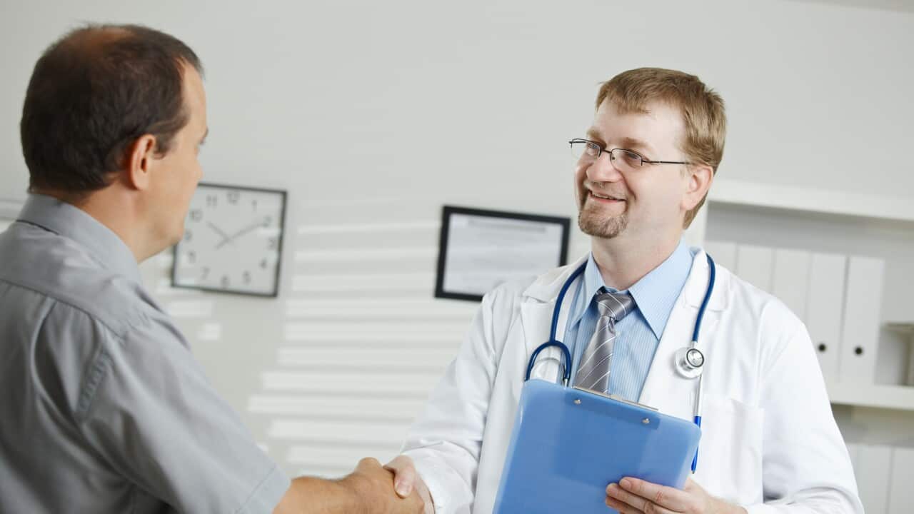 Medical office - middle-aged male doctor greeting patient, shaking hands.