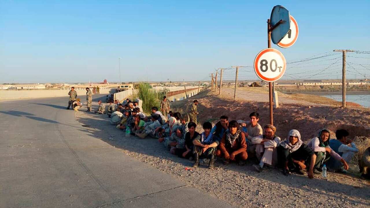 Afghanistan's government soldiers sit at a bridge next to Tajikistan-Afghanistan border in Tajikistan.