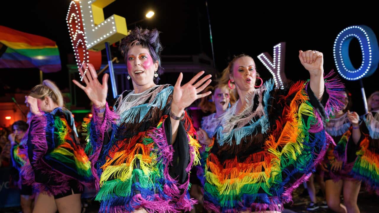 Participants wearing rainbow outfits march in Sydney Mardi Gras