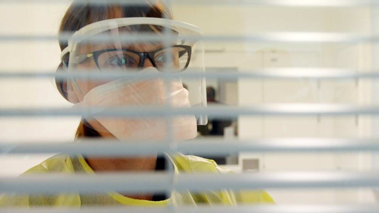 A nurse in protective gear in an isolation room