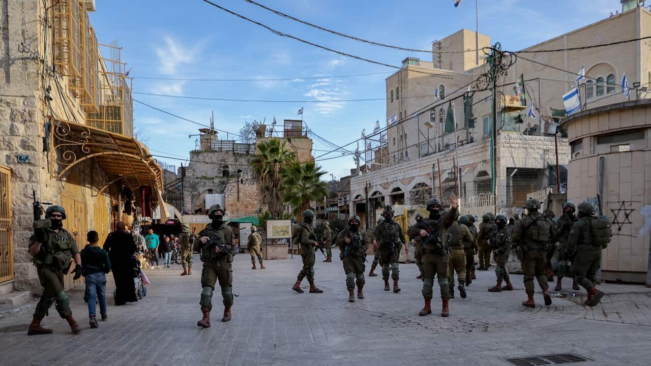 Soldiers in military fatigues carrying rifles walk through a city centre.