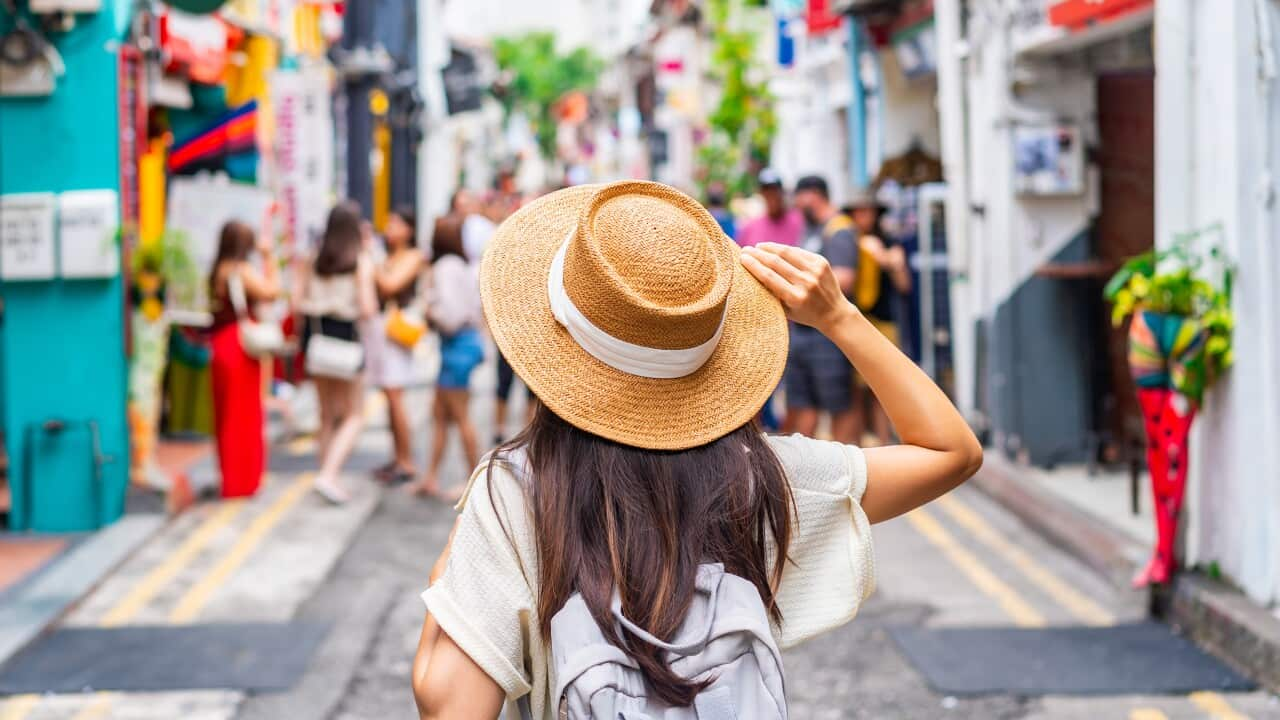 A woman walks through a colourful street.