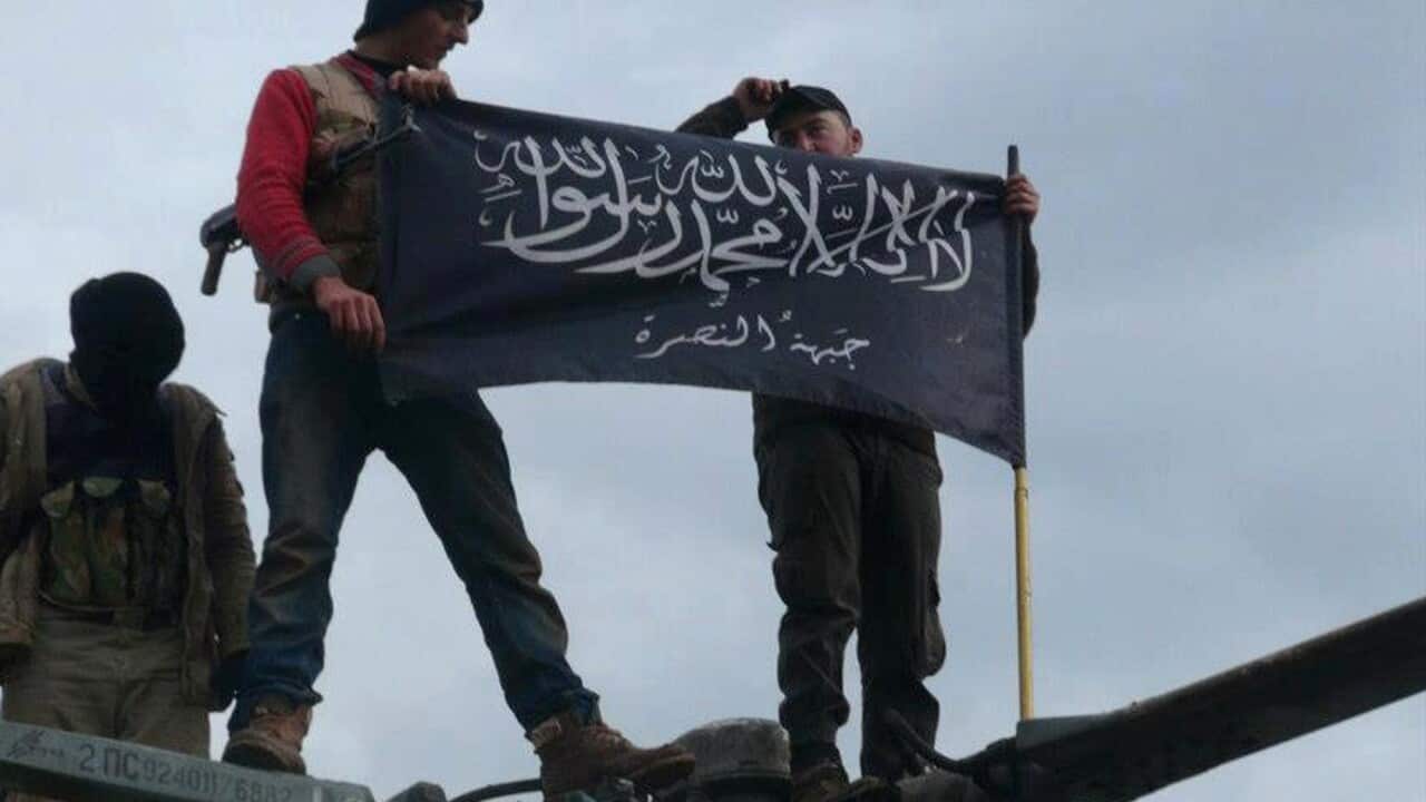 Rebels from al-Qaida-affiliated Jabhat al-Nusra, also known as the Nusra Front, wave their brigade flag, as they step on the top of a Syrian air force helicopter at Taftanaz air base (AP Photo/Edlib News Network ENN, File)