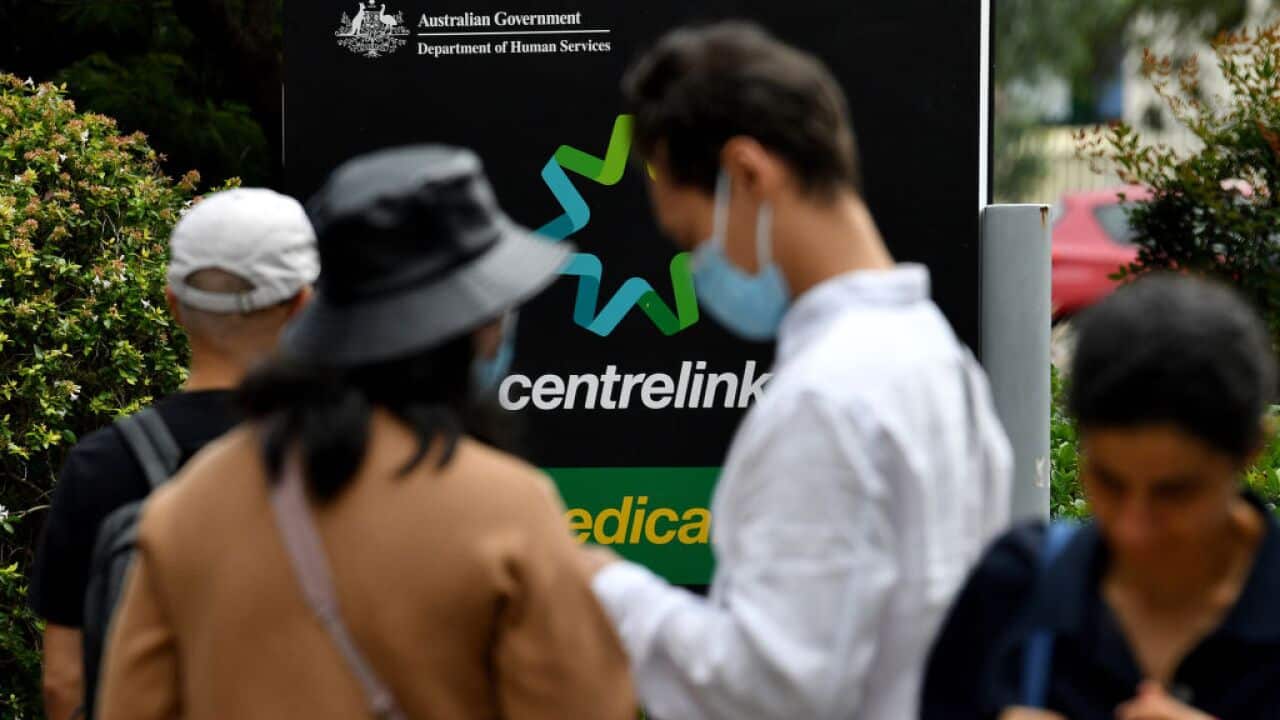 People wait in a queue to receive benefit payouts,