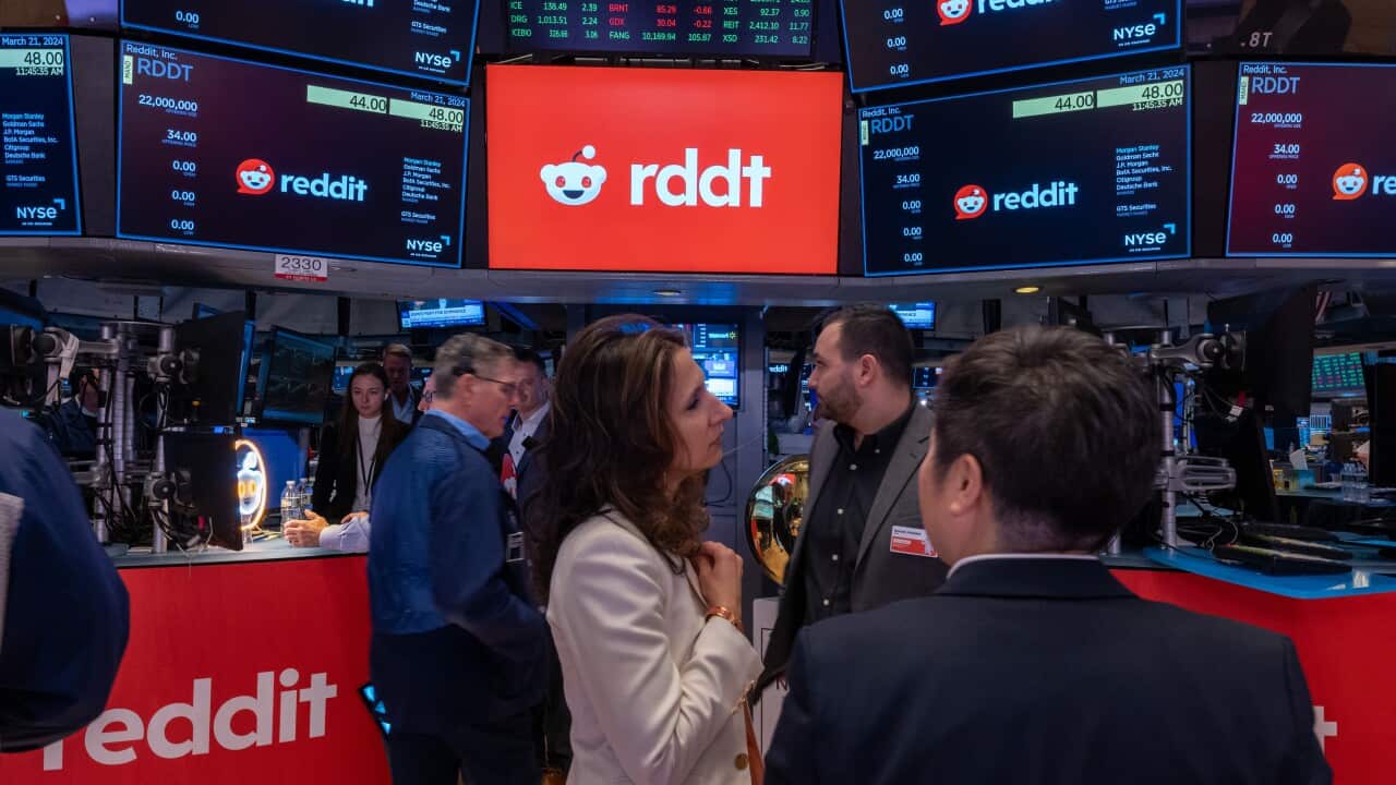 Stockbrokers standing inside looking at screens.