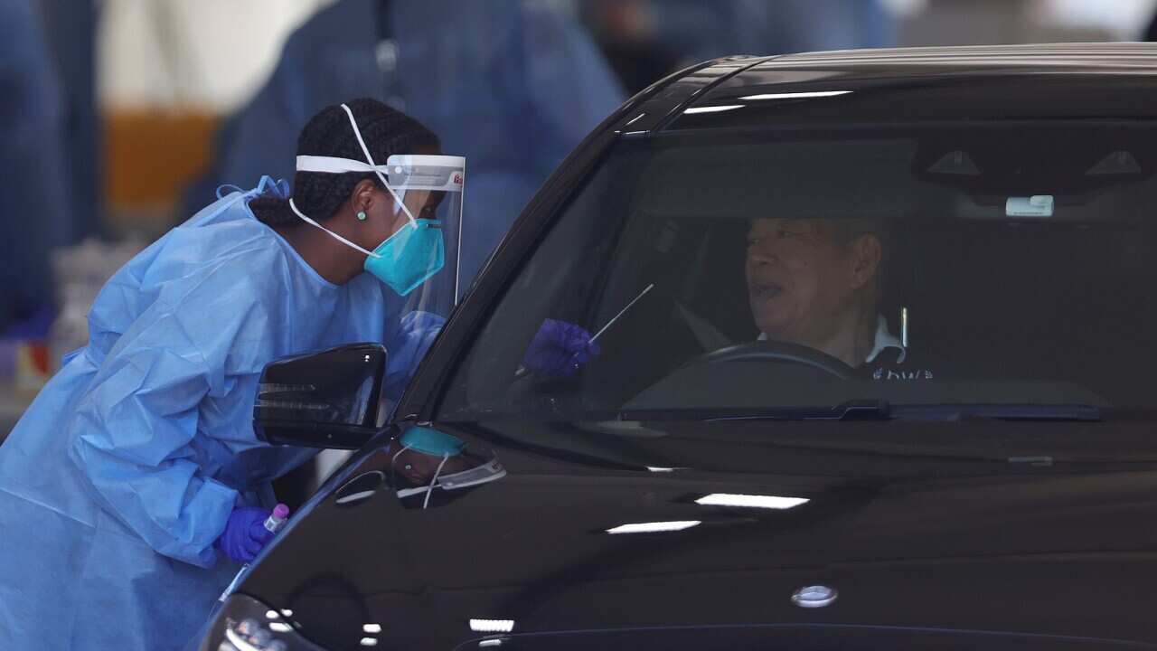 A health staff member is seen administering a PCR test at a drive-through COVID-19 testing site at Albert Park, in Melbourne,