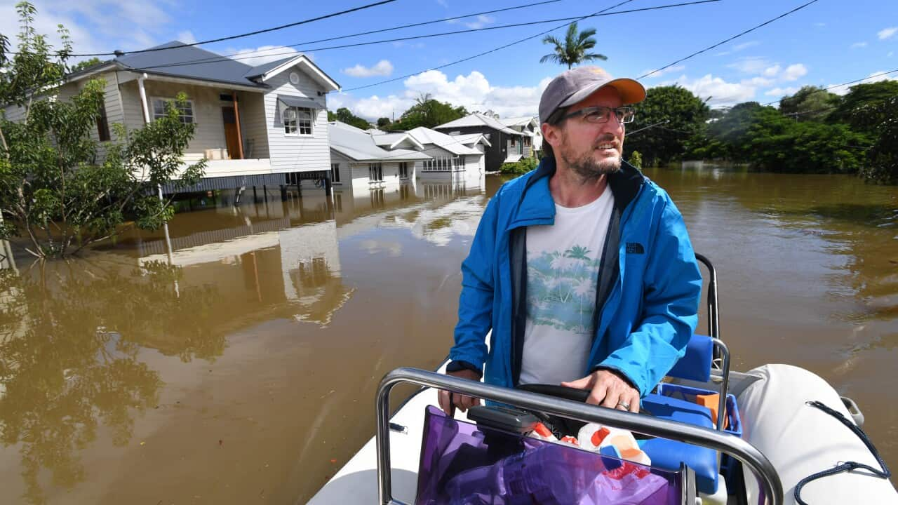 Auchenflower resident David Miller is seen navigating his boat along the street past flooded houses in the suburb of Auchenflower in Brisbane.