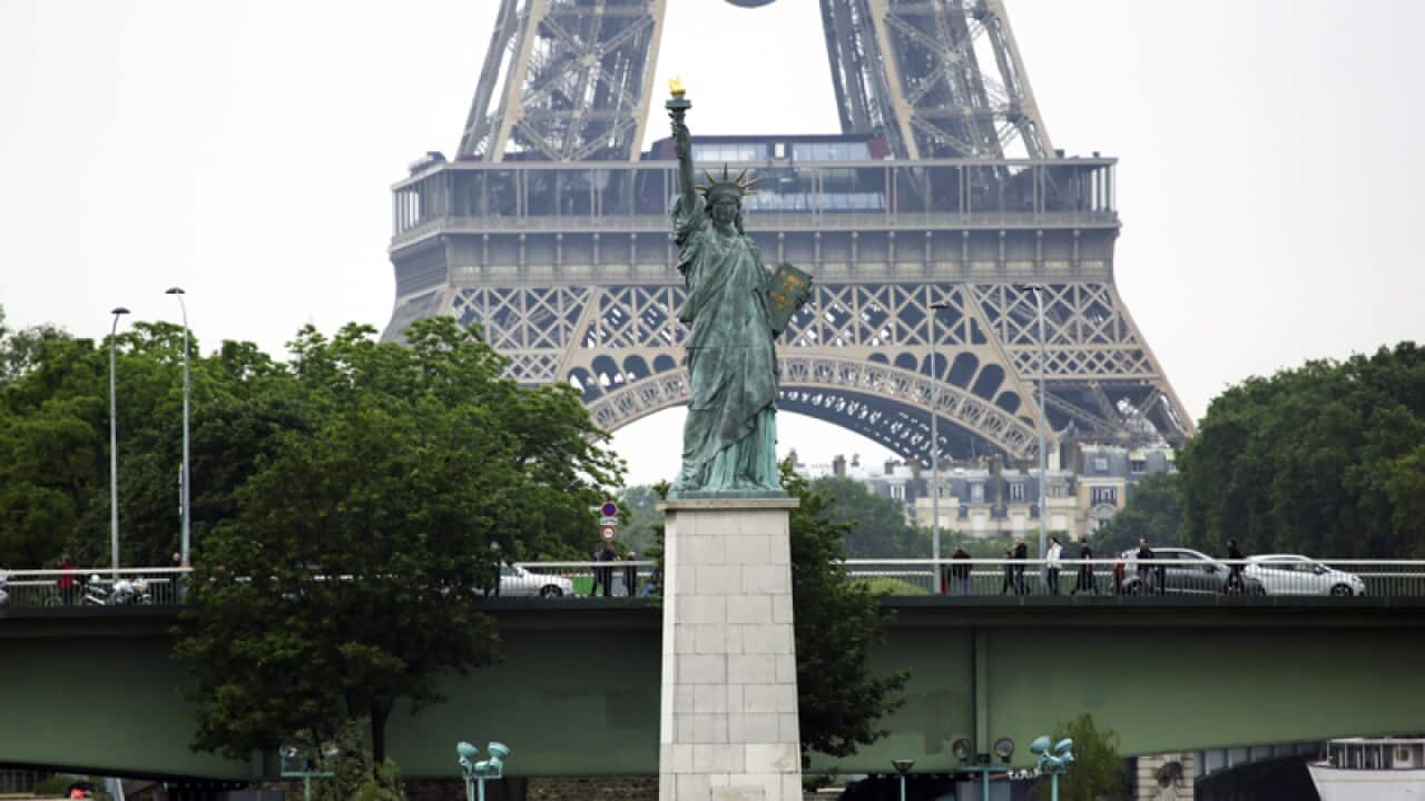 A replica Statue of Liberty stands over the flooded River Seine