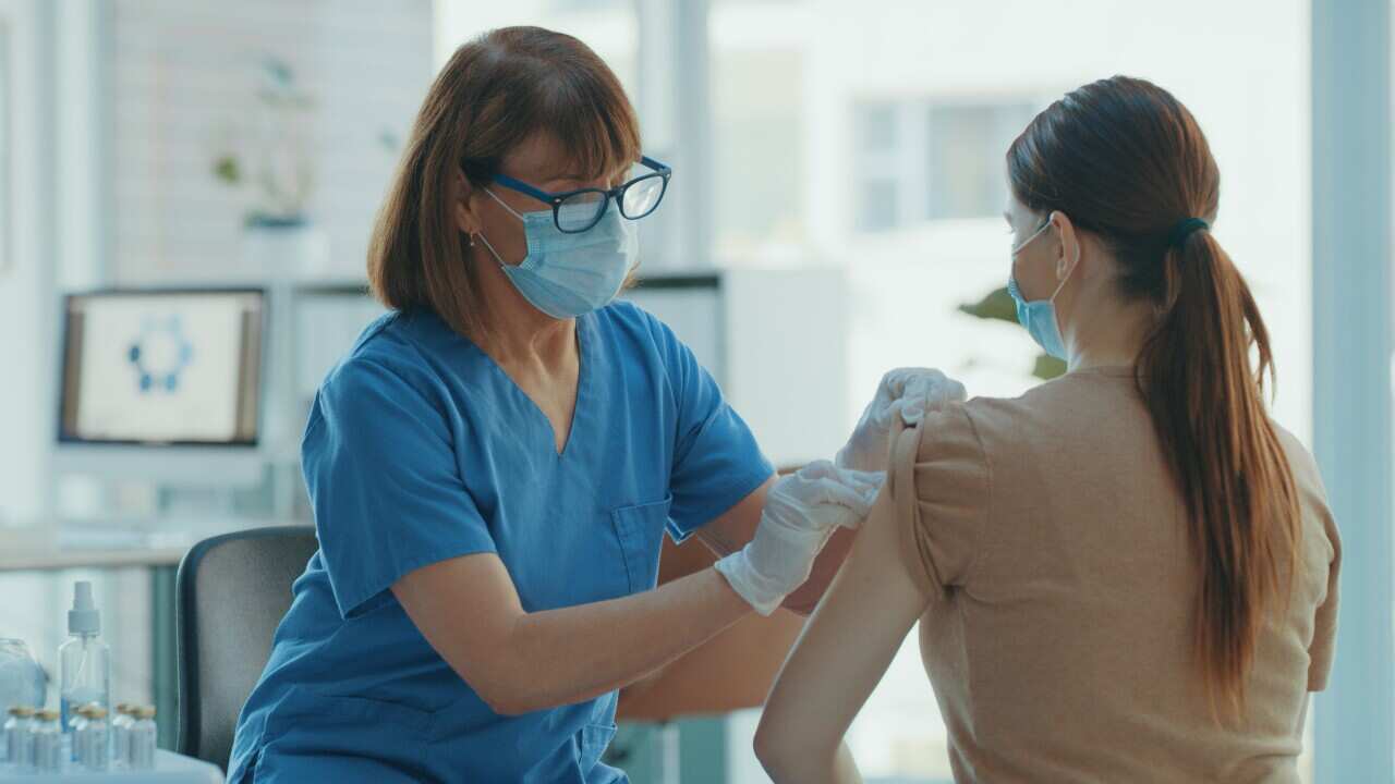 A doctor applying a bandaid to a patient's arm at a clinic.