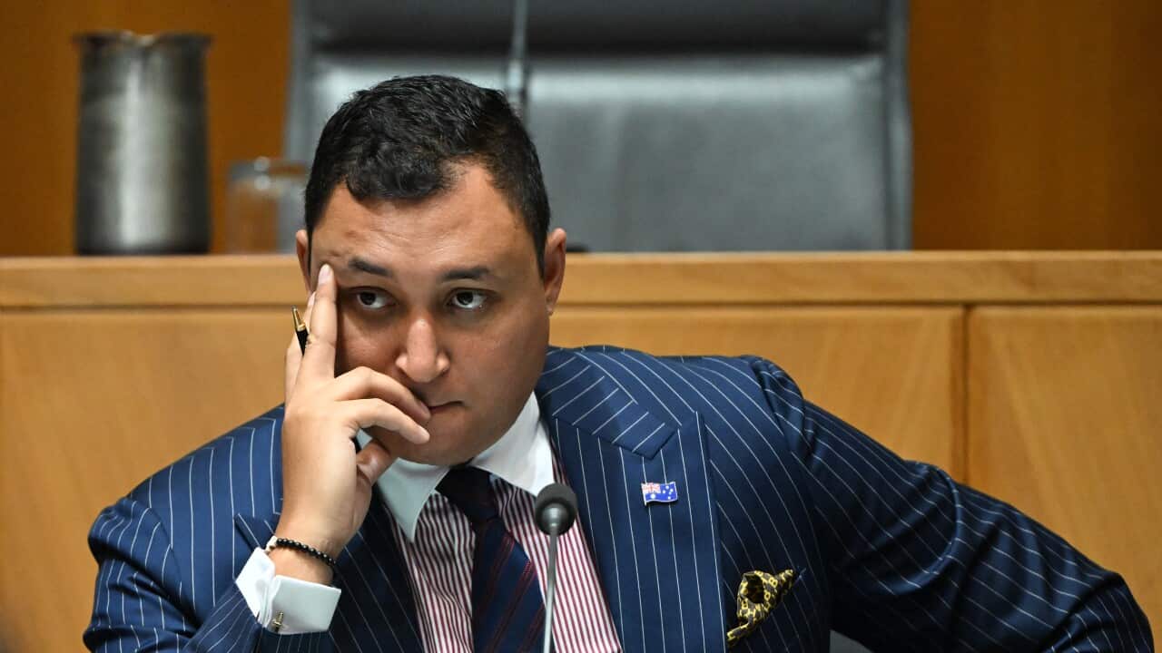 A man in a pinstriped suit listens during senate proceedings.