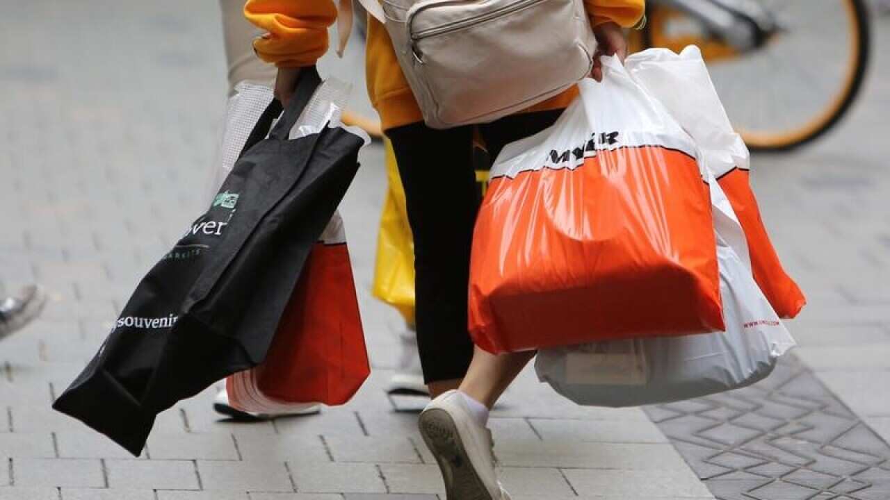 This is a file image of a shopper walking with several bags in Sydney.