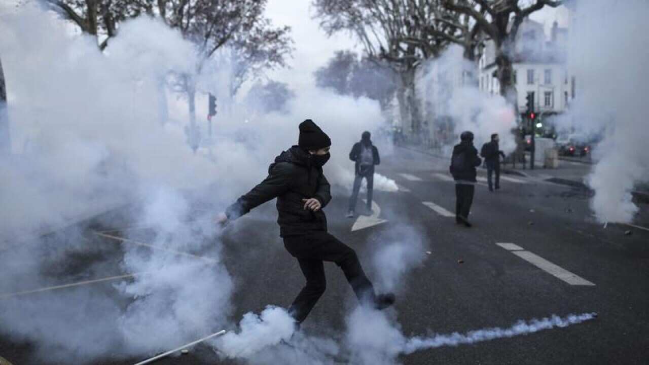 A yellow vest demonstrator kicks away a teargas canister