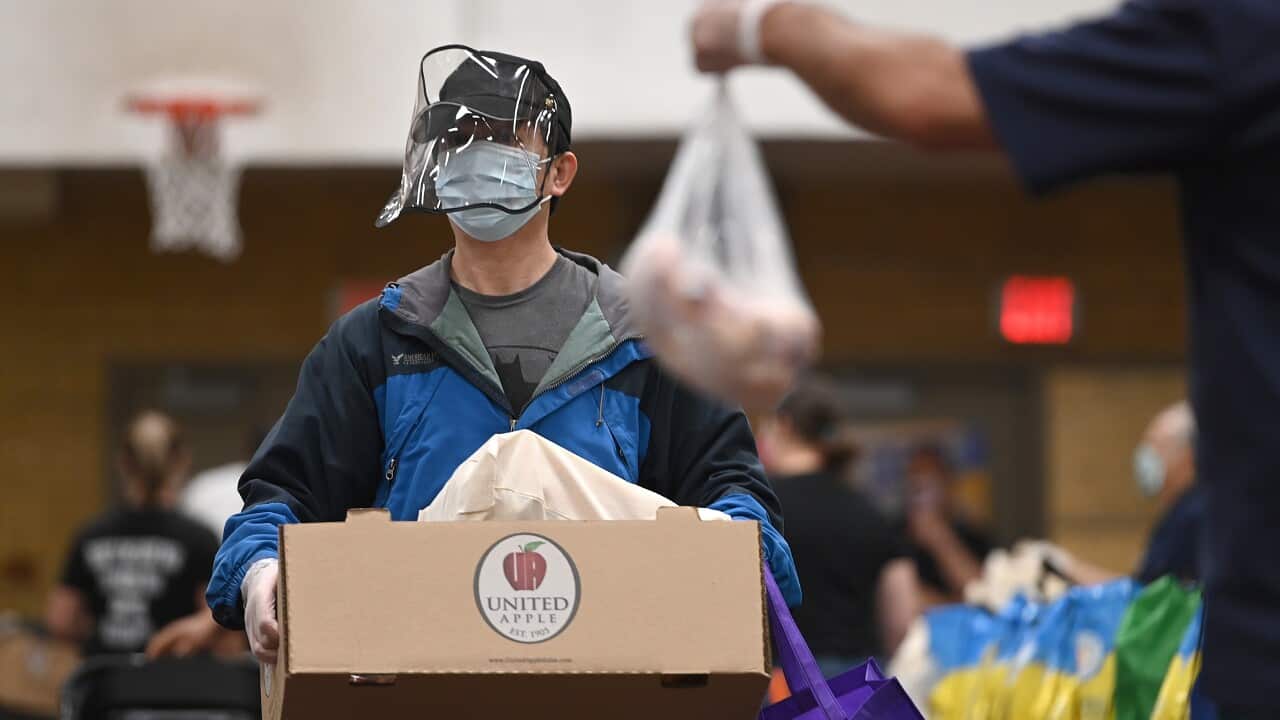 Wearing protective masks and gloves, volunteers help prepare and distribute donated food to people seeking assistance