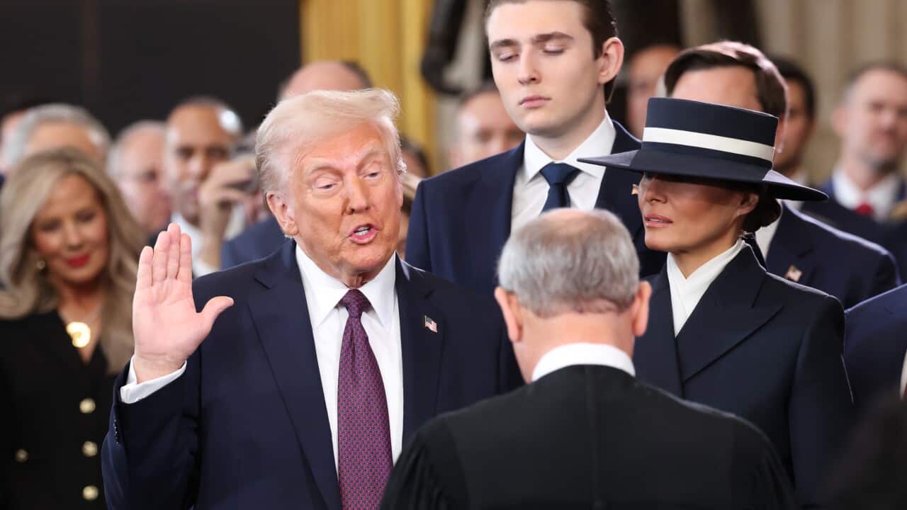 A man wearing a suit holding his hand up