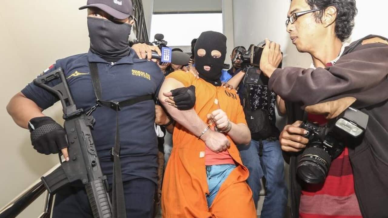 An Australian man is escorted by officers.
