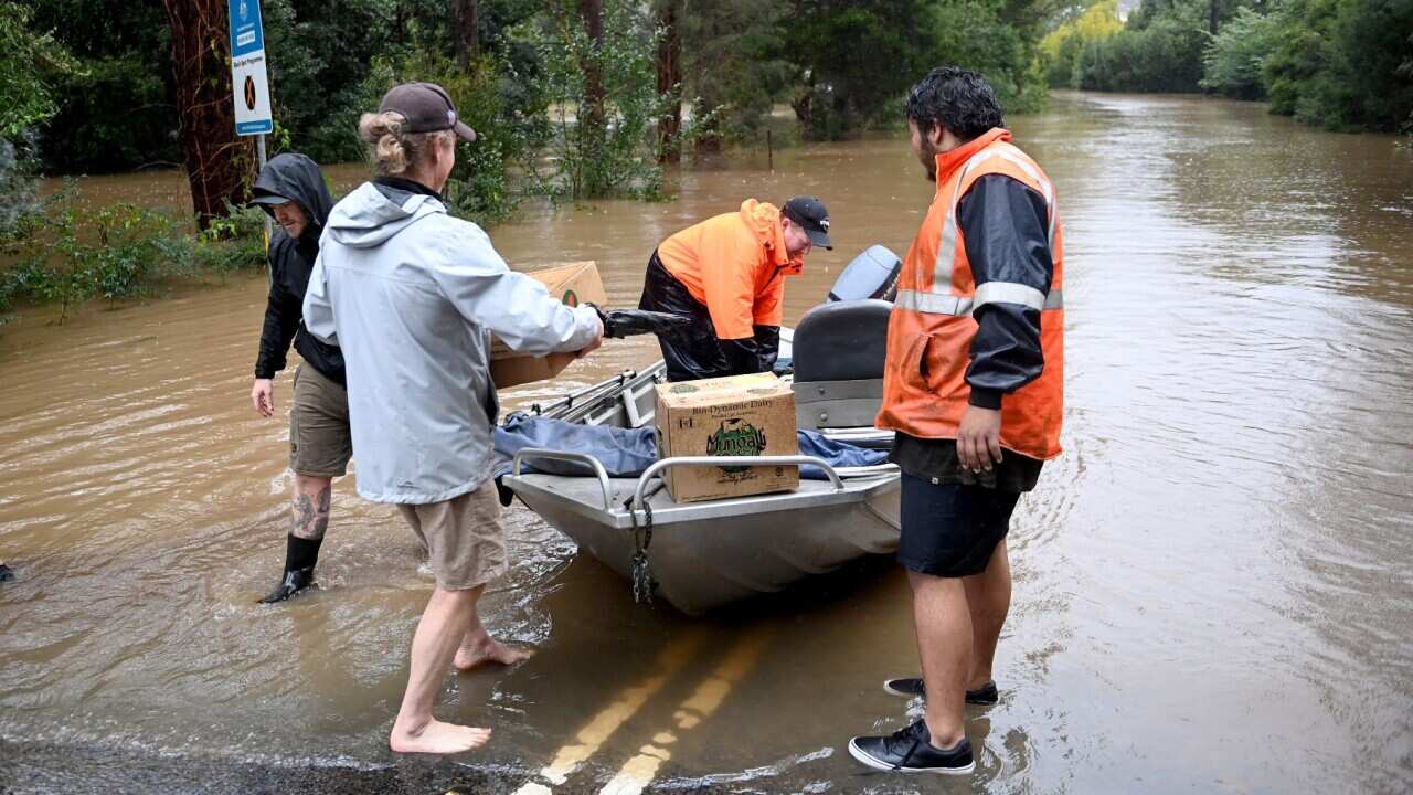 Local residents transport fuel and supplies across the flooded streets on small boats to stranded residents that are cut off by floodwaters which have inundate the NSW town of Yarramalong on the Central Coast, North of Sydney, Tuesday, July 5, 2022.