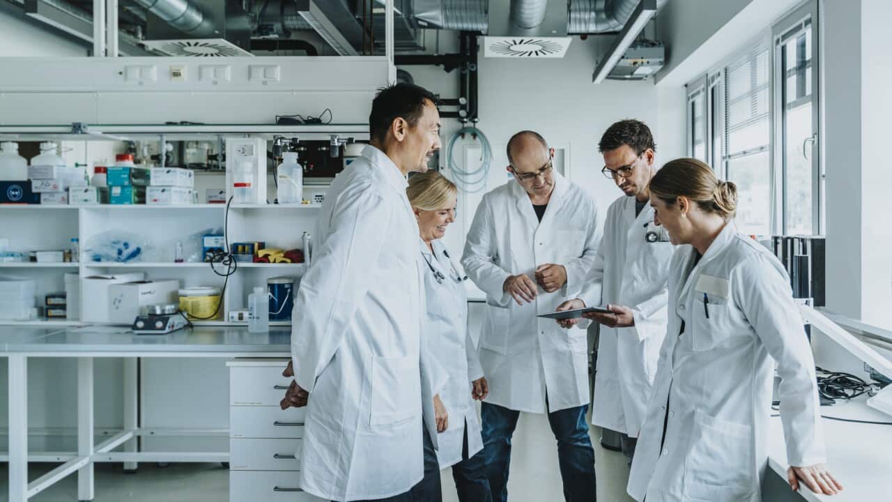 Team of scientist with digital tablet working together while standing at laboratory