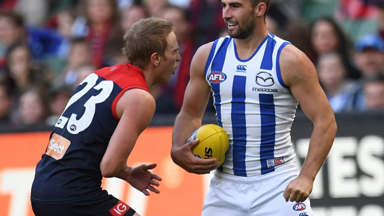 Ben Cunnington of the Kangaroos (R) punches Bernie Vince of the Demons