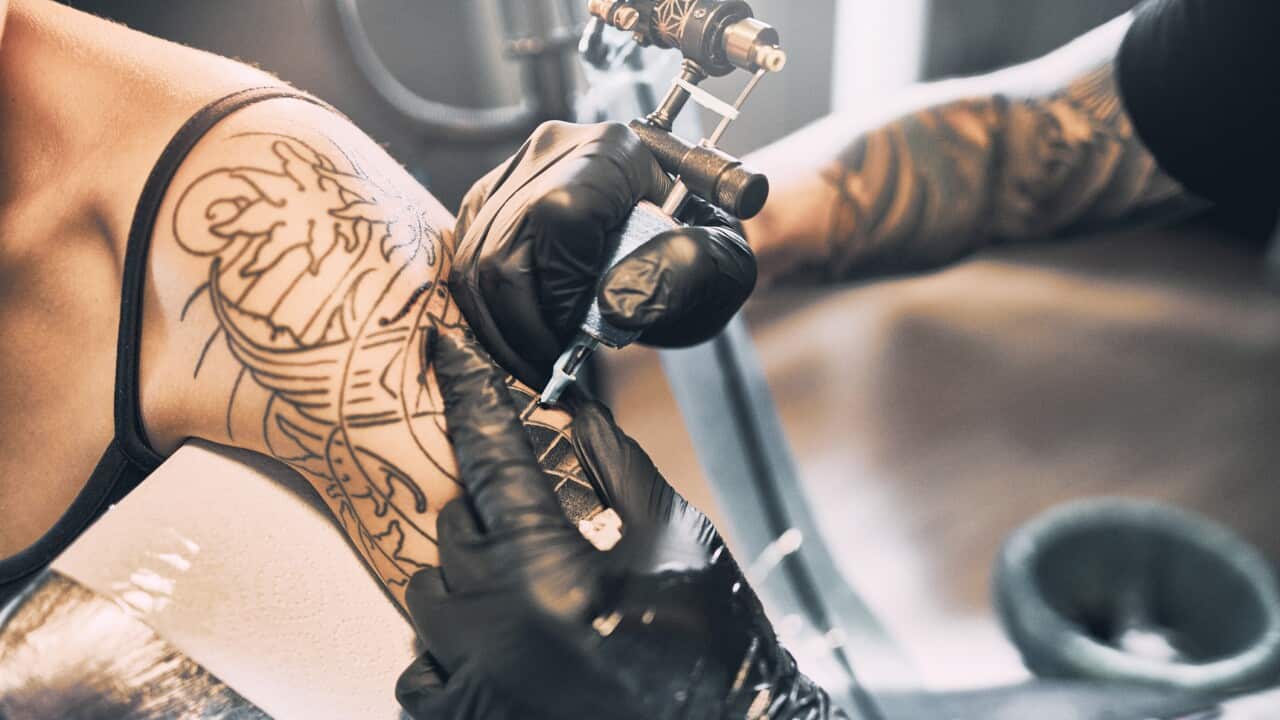 Artist Tattooing woman's shoulder