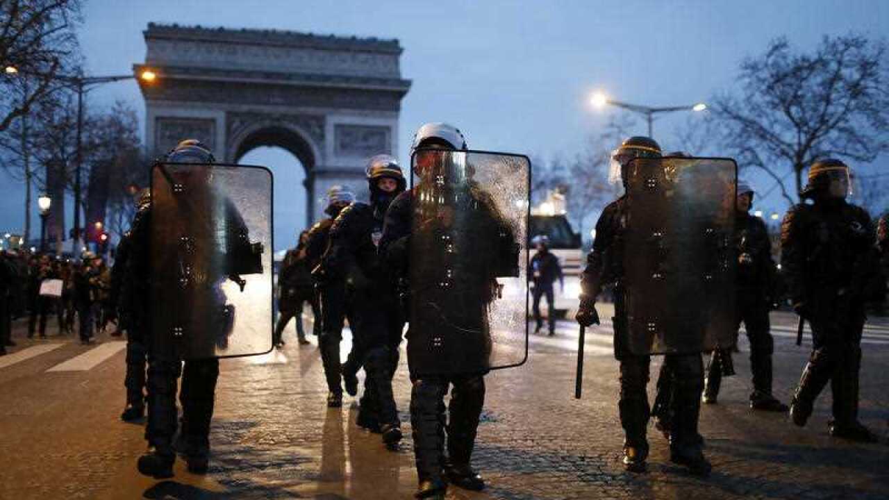 Riot police march towards gathered Yellow Vest protesters in Paris.