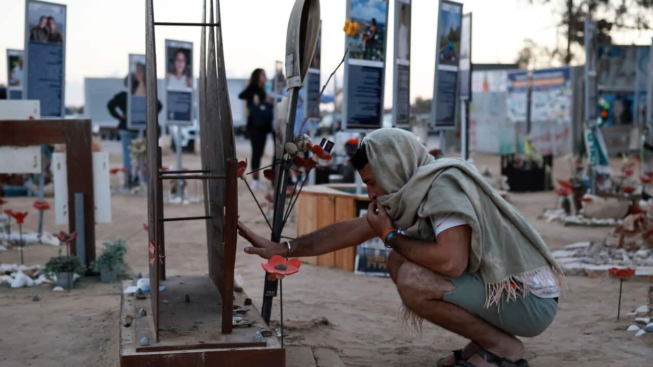 A man wearing a headscarf bows his head at a memorial site for victims of the October 7 attack.
