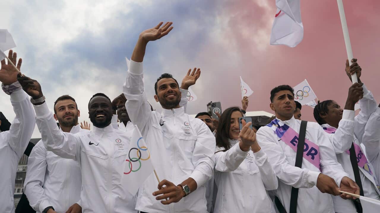 A group of people wave while some hold flags.