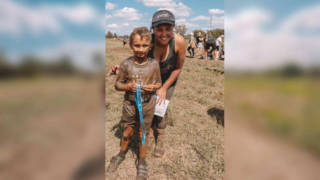 A woman is seen smiling with her child at a tough mudders event.