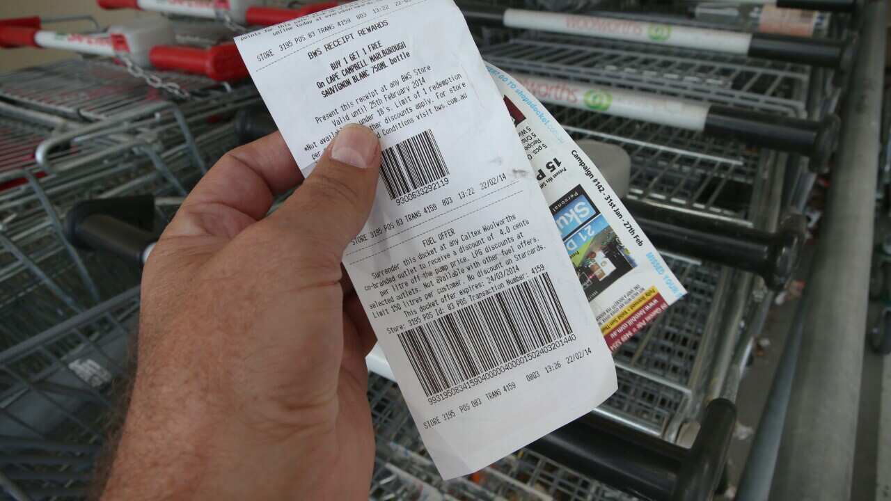 A man carried a receipt in front of trolleys.