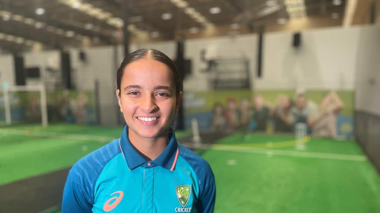 Hasrat Gill smiling to the camera, wearing a Cricket Australia training outfit at an indoor training facility